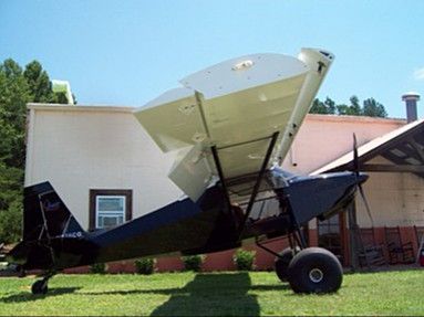 an airplane sitting on top of a grass covered field next to a building and trees