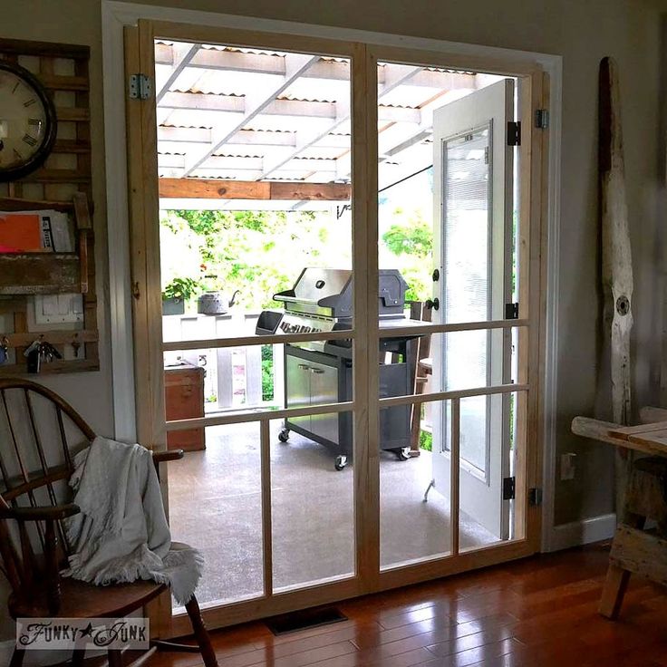 an open glass door leading to a room with a desk and chair in it,