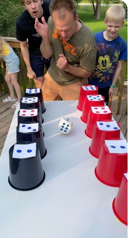 a group of people standing around a table with dices on it and one man pointing at them