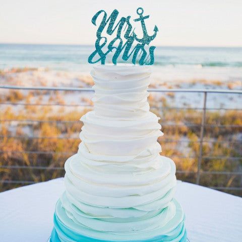 a white and blue cake sitting on top of a table next to the ocean,