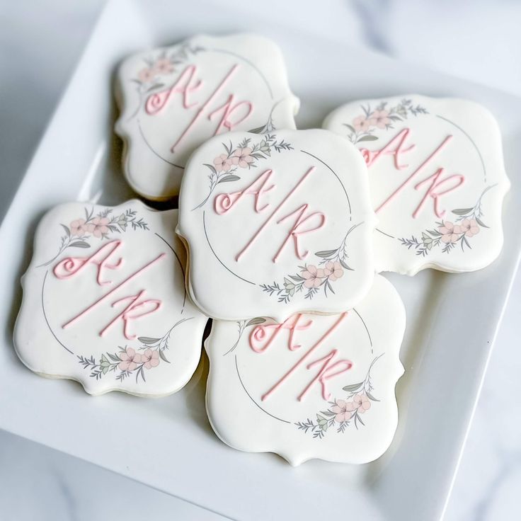 four decorated cookies on a white plate with pink and gray lettering that says mr and mrs