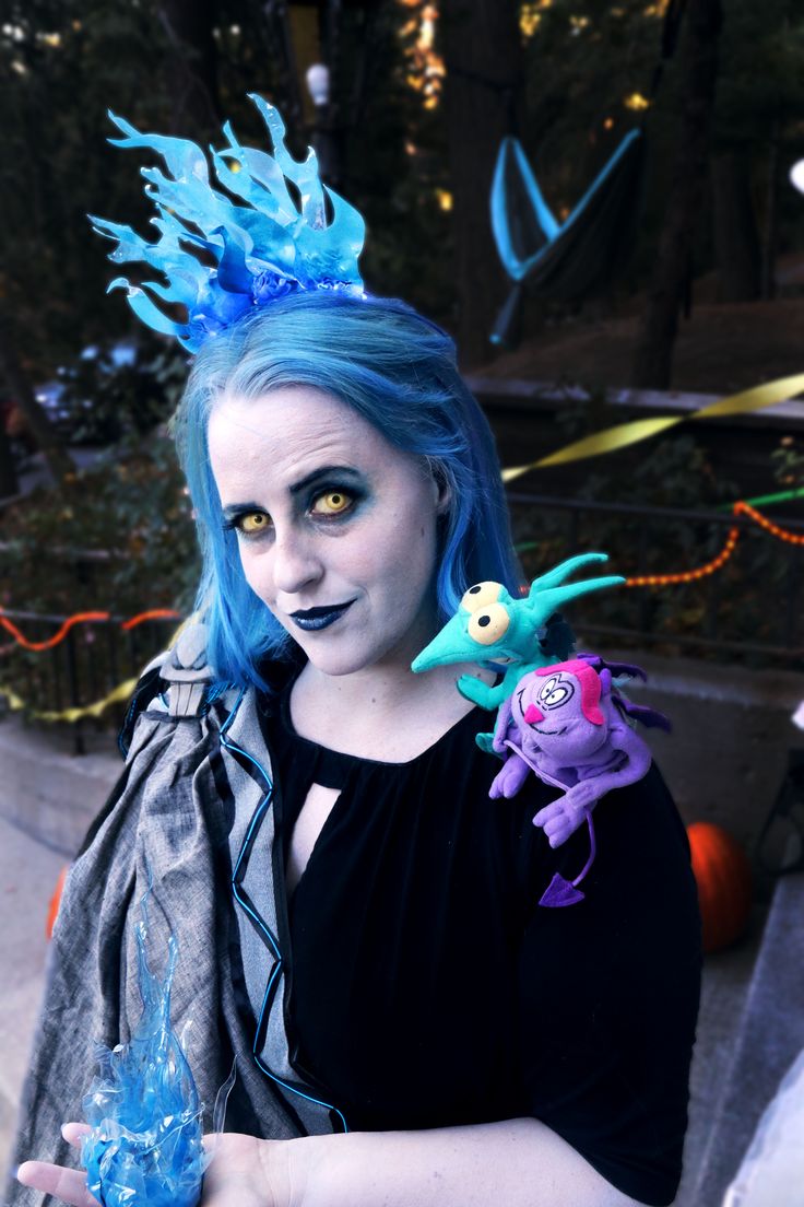 a woman with blue hair and makeup is holding something in her hand while wearing monster costumes