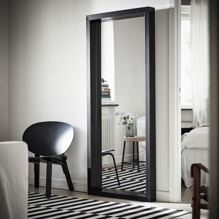 a black and white striped rug in front of a large mirror with a chair next to it