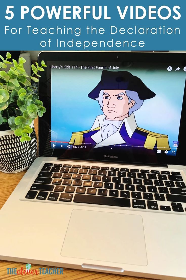 an open laptop computer sitting on top of a wooden table next to a potted plant