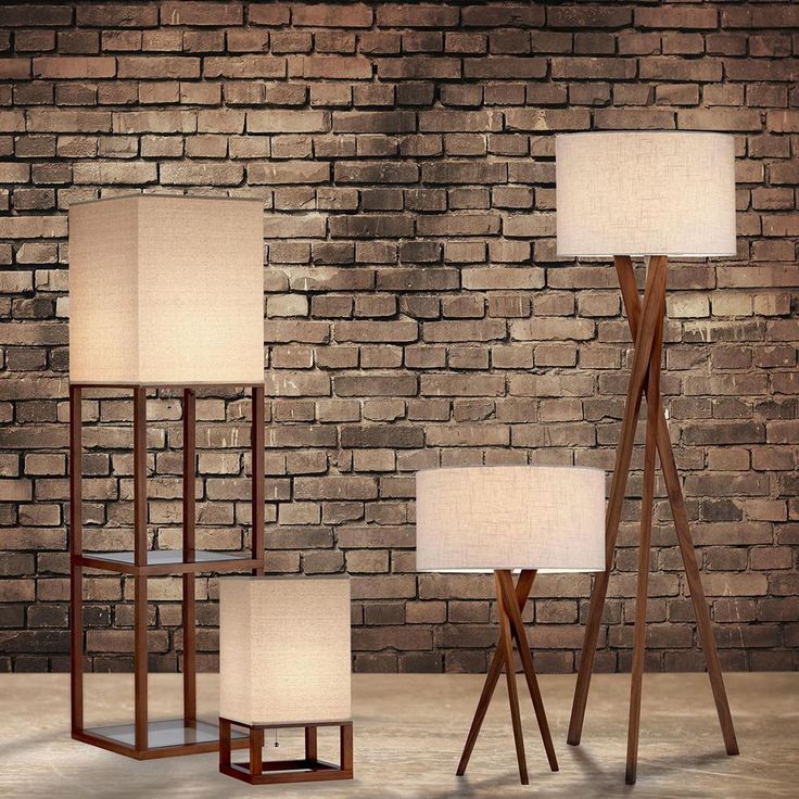 three floor lamps in front of a brick wall