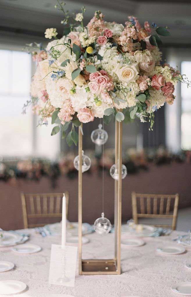 an elegant centerpiece with pink and white flowers sits on top of a round table