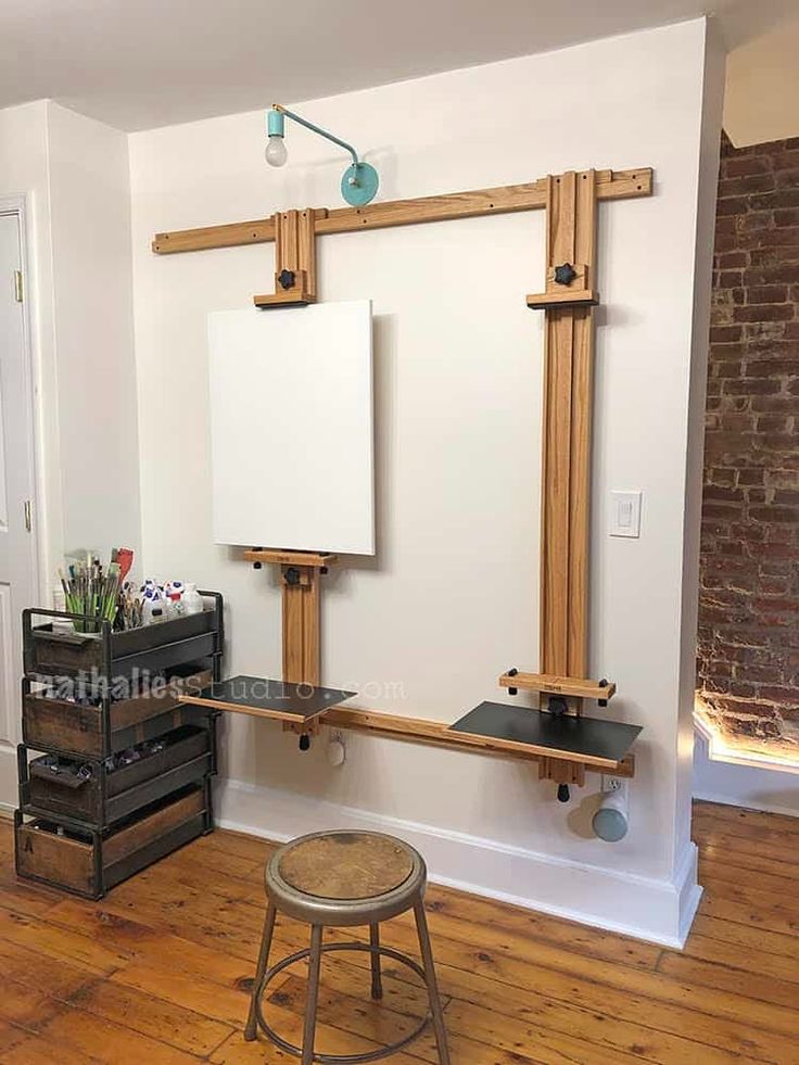 an empty room with two easels and a desk in it, next to a brick wall