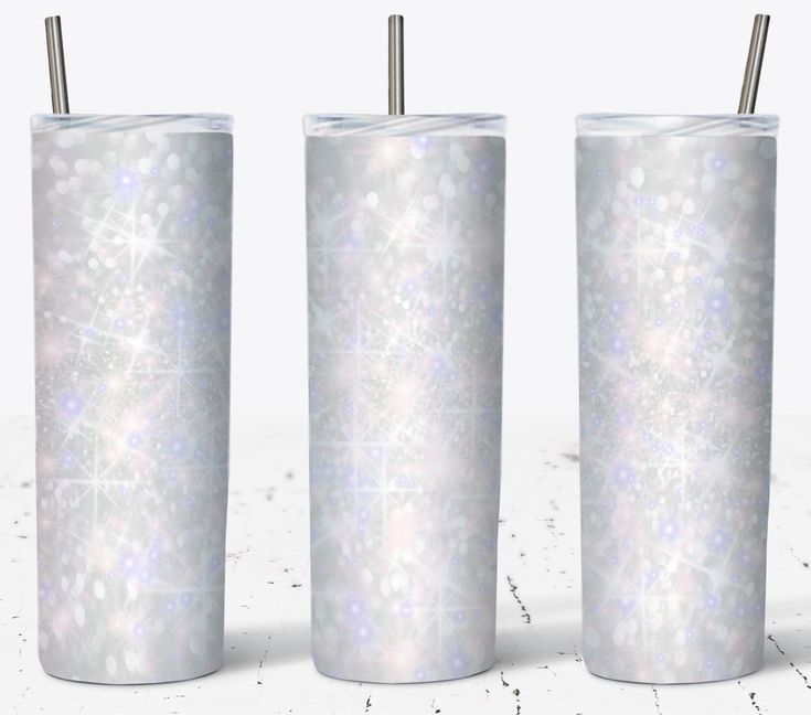 three white tumblers with straws in them on a marble countertop and one has snowflakes all over it