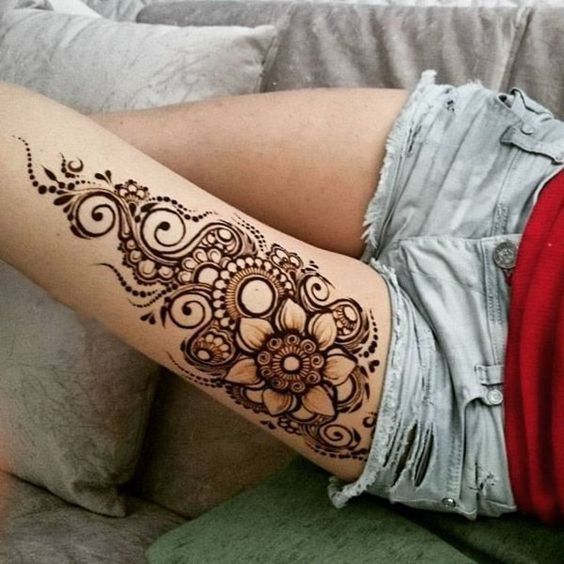 a woman's arm with a henna tattoo on her left arm and legs