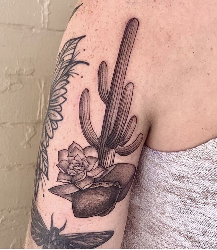 a woman's arm with a cactus and flower tattoo on the back of her shoulder