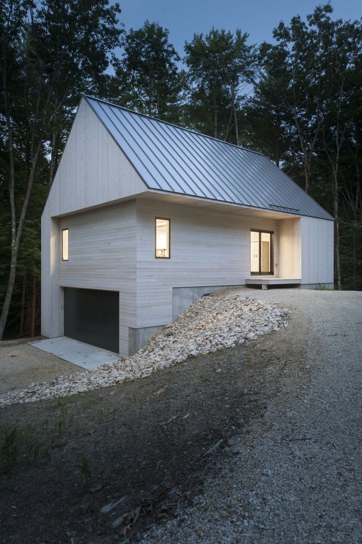 a white house sitting on top of a gravel hill next to trees and bushes at night