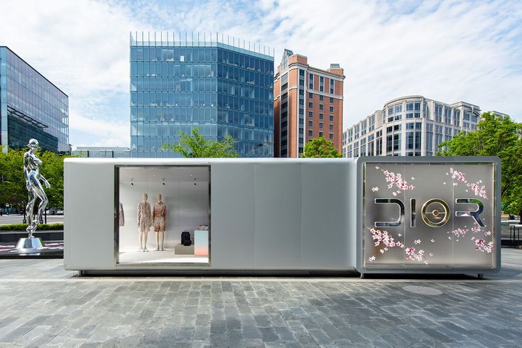 an open display case in the middle of a plaza with buildings and trees behind it