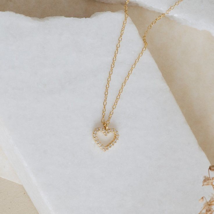 Whether you are celebrating a special occasion, or just feeling like treating yourself, this delicate necklace will become an everyday staple piece in your jewelry collection. The Forever Pave Heart Necklace is the perfect symbol of self-love and empowerment. With a diamond encrusted open heart charm, the design is perfect for brides and bridal parties, it's dainty enough to complement every look. Material: High-Quality Solid 925 Sterling Silver Finish: Sterling Silver ∙ 18K Gold Featuring a 9mm Delicate Open Heart Charm Necklace With Delicate Chain, Dainty Heart Birthstone Necklace For Valentine's Day, Valentine's Day Dainty Heart Birthstone Necklace, Delicate Heart Pendant Charm Necklace With Adjustable Chain, Delicate Heart Necklace With Adjustable Chain, Delicate Open Heart Necklace With Delicate Chain, Delicate Open Heart Chain Necklace, Delicate Heart Pendant Charm Necklaces, Dainty Heart Pendant Charm Necklace For Everyday