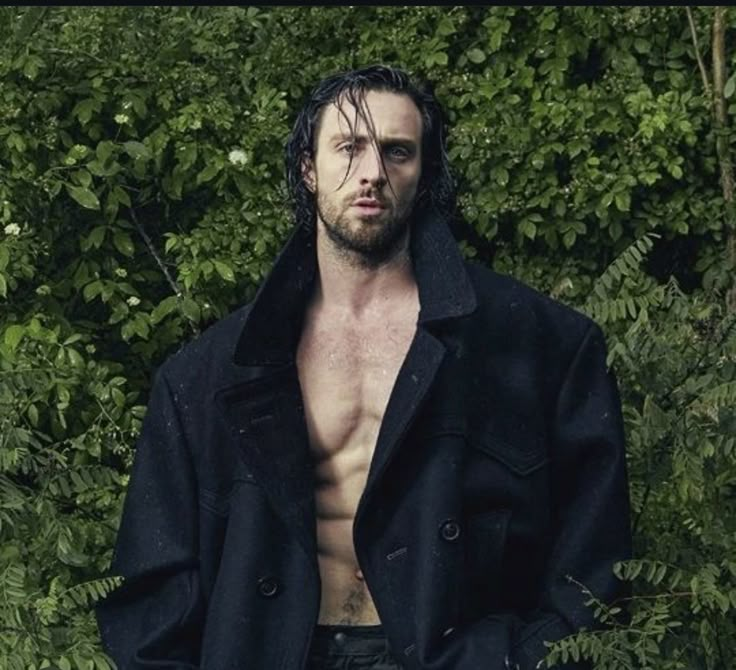 a shirtless man standing in front of some bushes