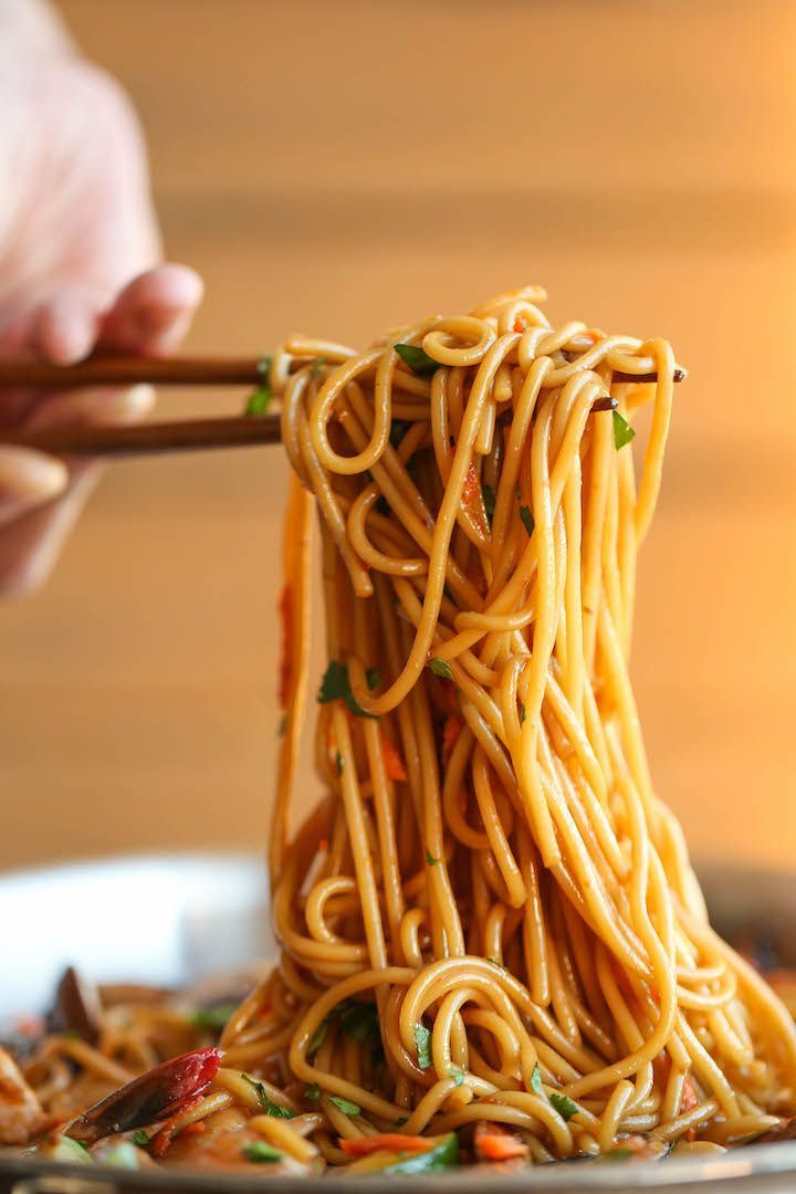 someone is holding chopsticks over noodles on a plate