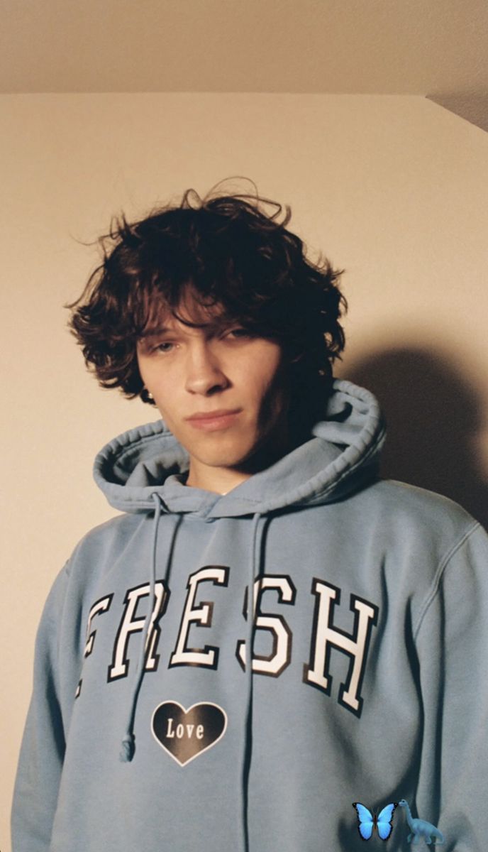 a young man wearing a blue hoodie with a heart on the front and words fresh above it