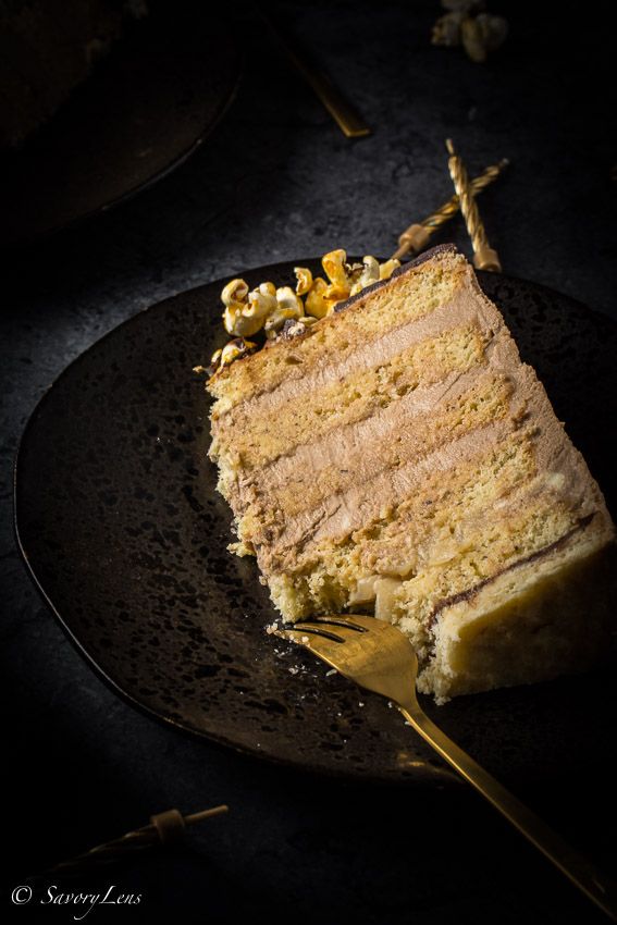 a piece of cake on a black plate with a gold fork in front of it