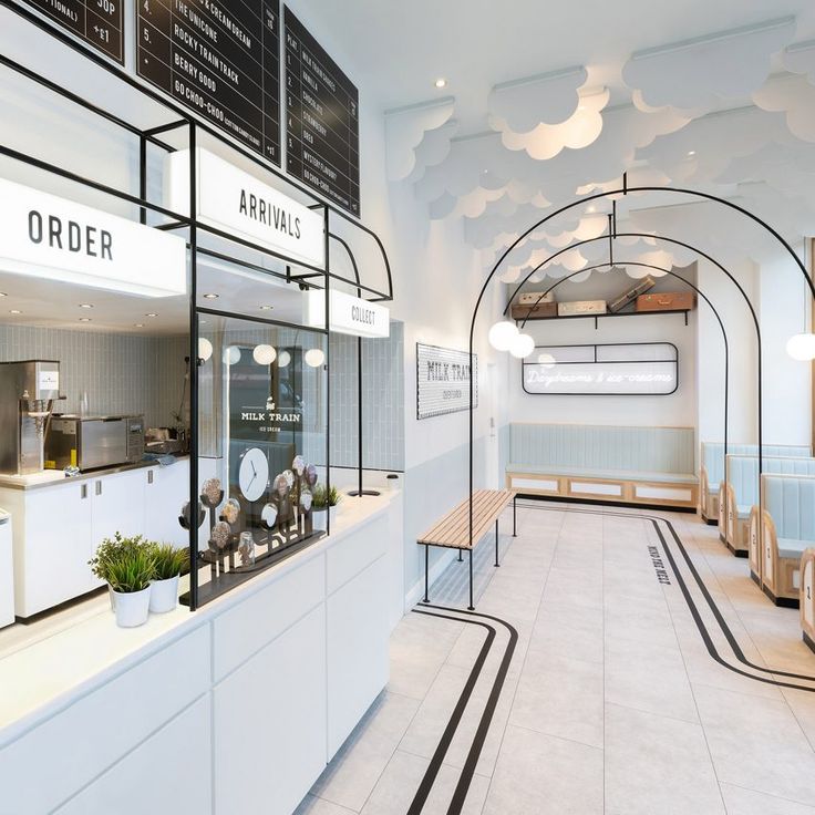 the interior of a restaurant with white walls and black trim on the ceiling, along with tables and benches