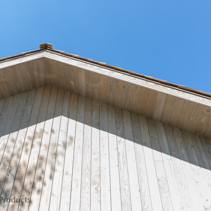 a bird is perched on the roof of a building with a blue sky in the background