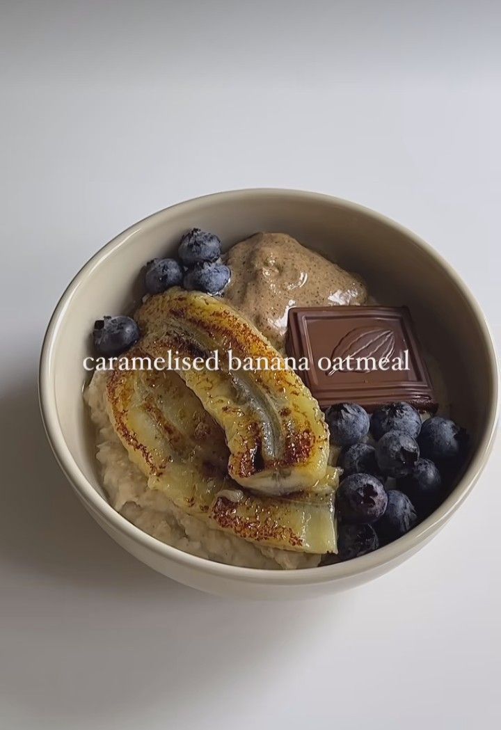 a bowl filled with bananas and blueberries next to a bar of chocolate on top