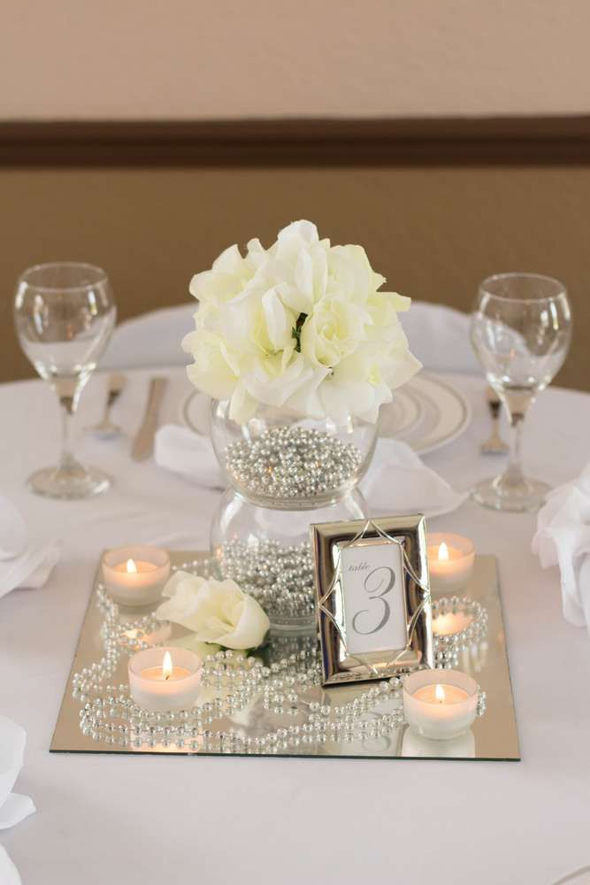 the centerpieces on this table are decorated with white flowers and candles for an elegant touch