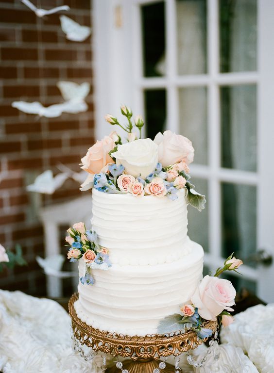 a white wedding cake with pink and blue flowers