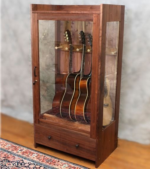 a wooden case with guitars in it on top of a rug next to a wall