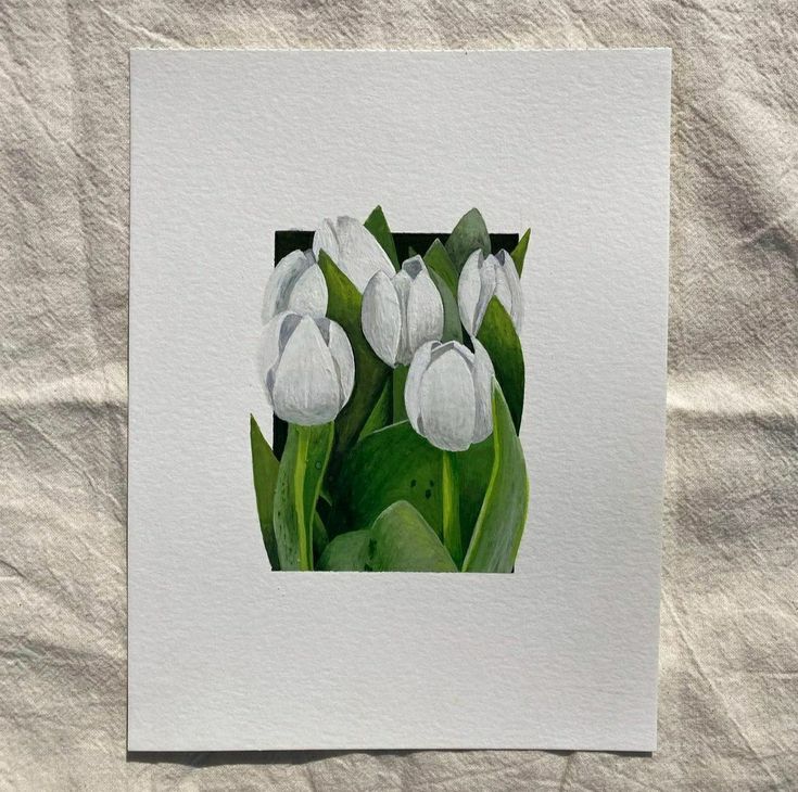 some white flowers are sitting in the middle of green leaves on a piece of paper