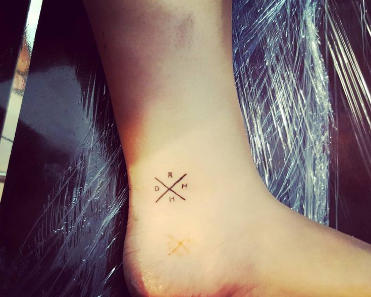 a small tattoo on the foot of a person with two crossed crosses in it's center