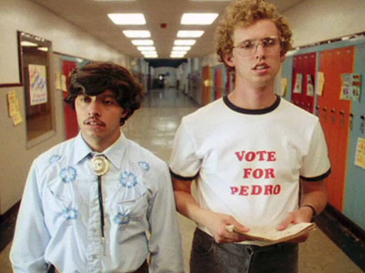 two young men standing next to each other in a hallway with posters on the walls