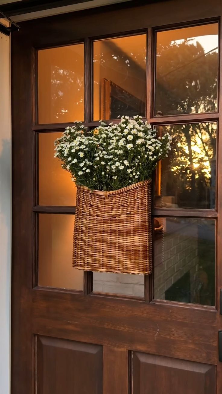 a basket filled with flowers hanging from the side of a wooden door next to a window