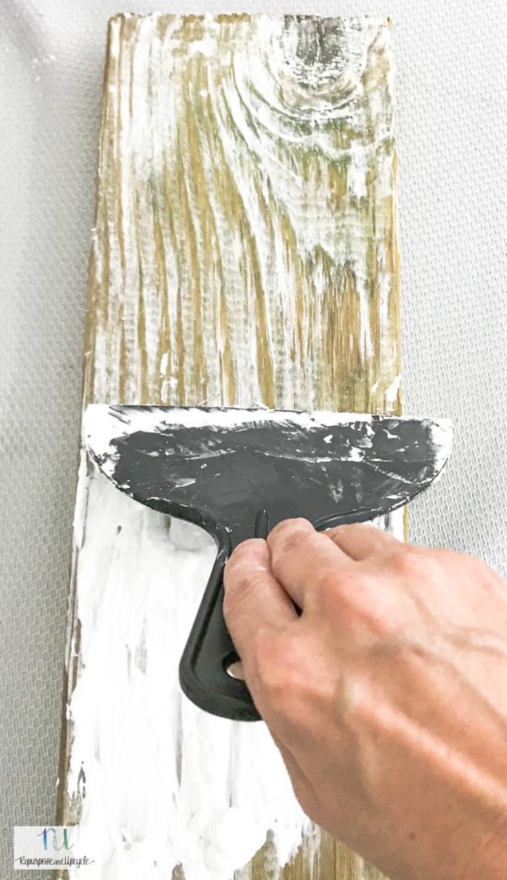 a person using a paint brush to paint a piece of wood