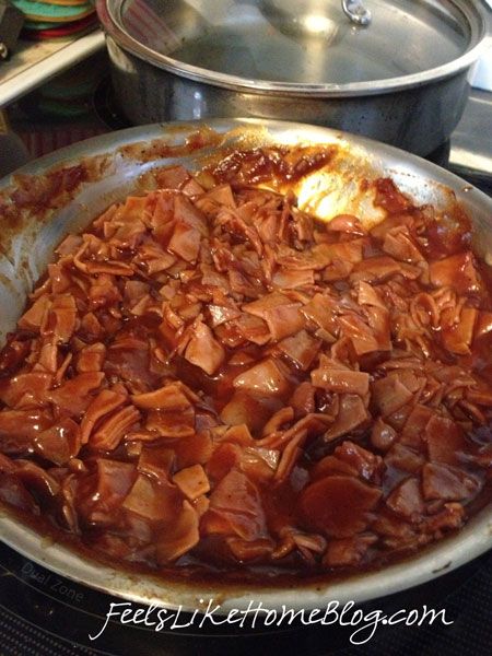 a pan filled with meat sitting on top of a stove next to a pot full of food