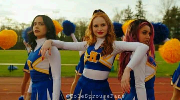 three girls in cheerleader outfits standing on a field