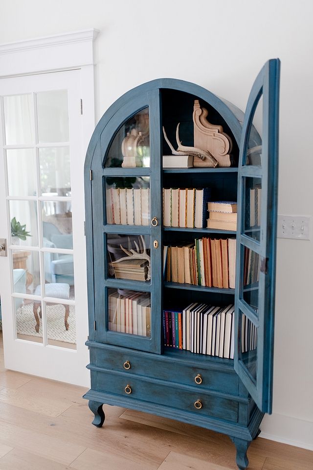 a blue bookcase with books in it on the floor next to a white wall