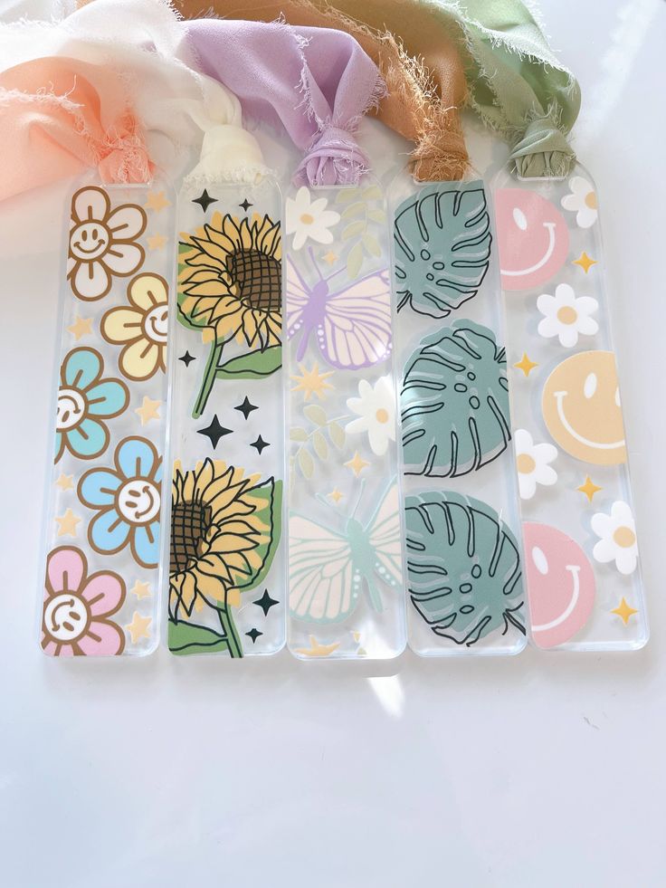 four decorative bookmarks with flowers and butterflies on them, sitting next to each other