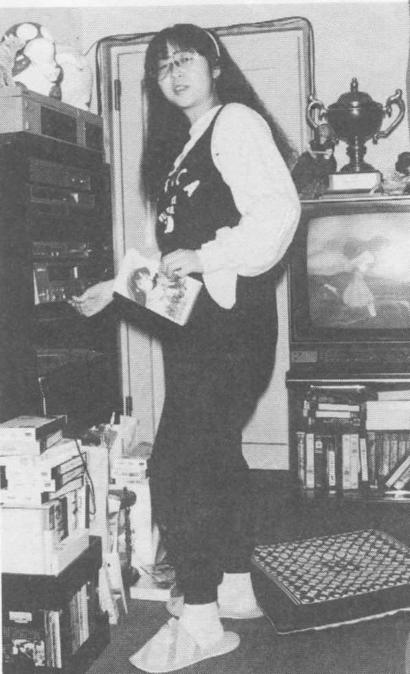 an old photo of a woman standing in front of a tv and holding a book