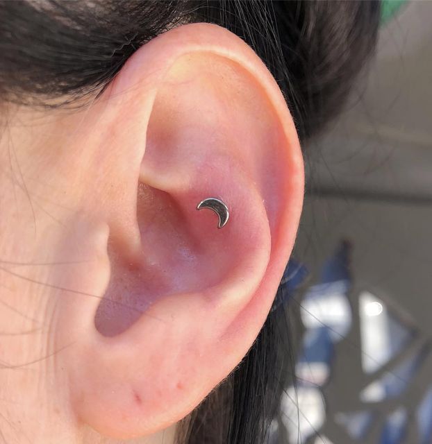 a woman's ear with a small crescent piercing