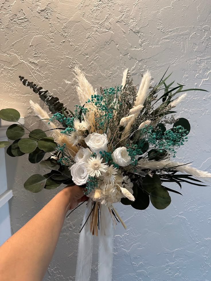 a person holding a vase with flowers and greenery