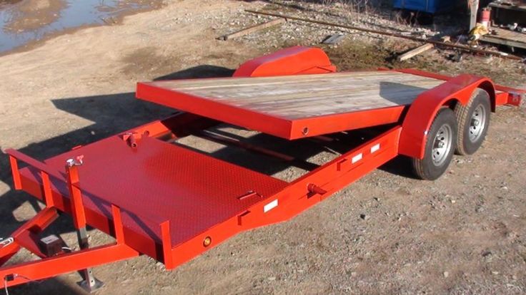 an orange trailer sitting on top of a dirt field next to a body of water