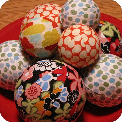 several colorful balls are stacked on top of each other in a red bowl with white and green polka dots