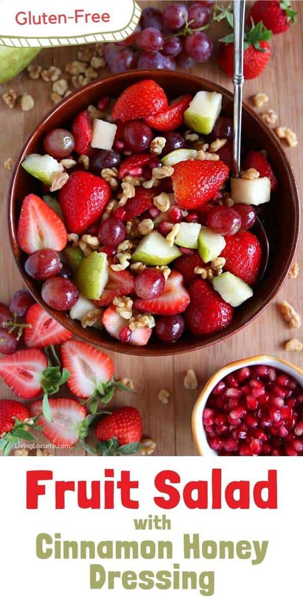 fruit salad with cinnamon honey dressing in a bowl on a wooden table next to grapes and strawberries