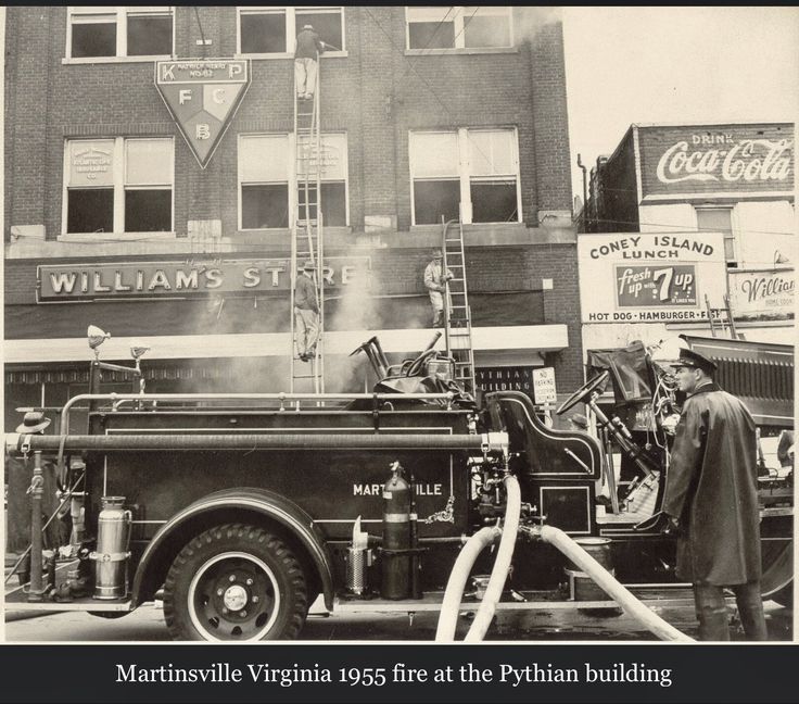 an old black and white photo of a fire truck in front of a tall building