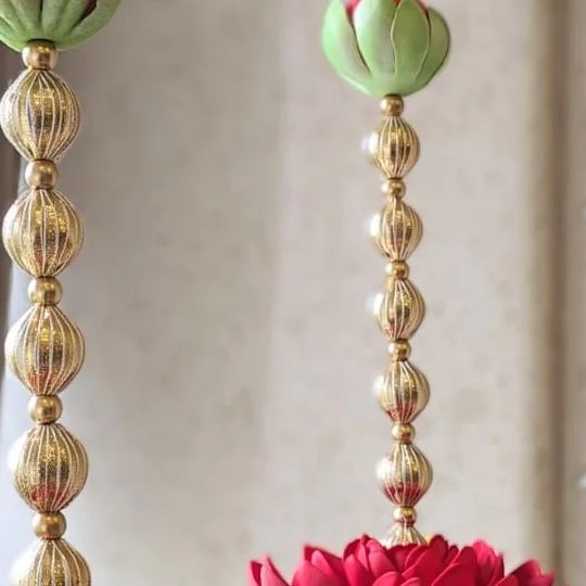 two gold vases with flowers hanging from them