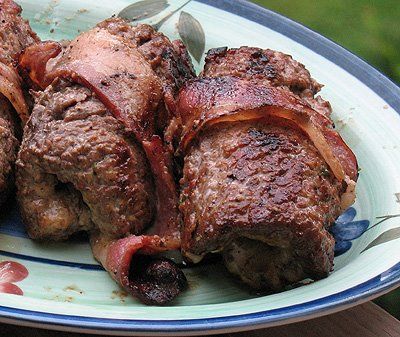 some meat is sitting on a plate with a knife and fork next to the meat