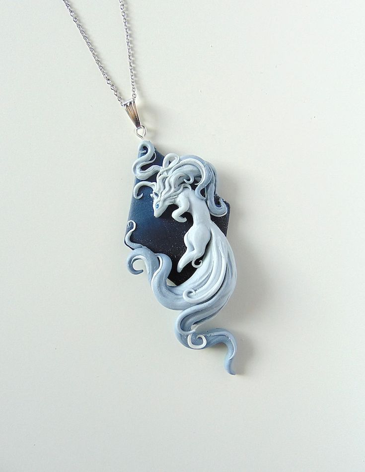 a blue and white necklace with a horse on it's back end hanging from a silver chain