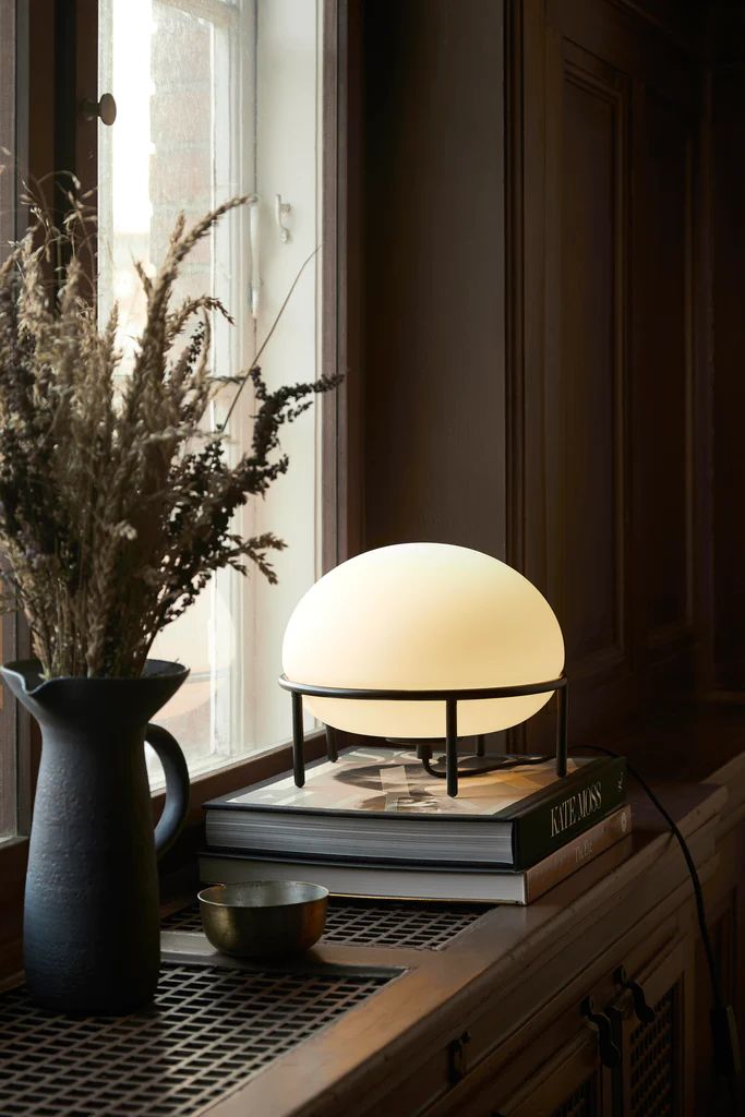 a table lamp sitting on top of a book next to a vase