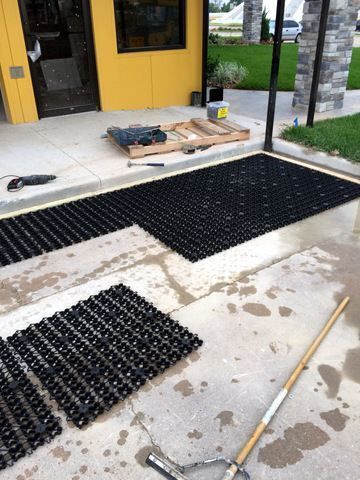 a pair of shovels laying on the ground in front of a yellow door with black grates