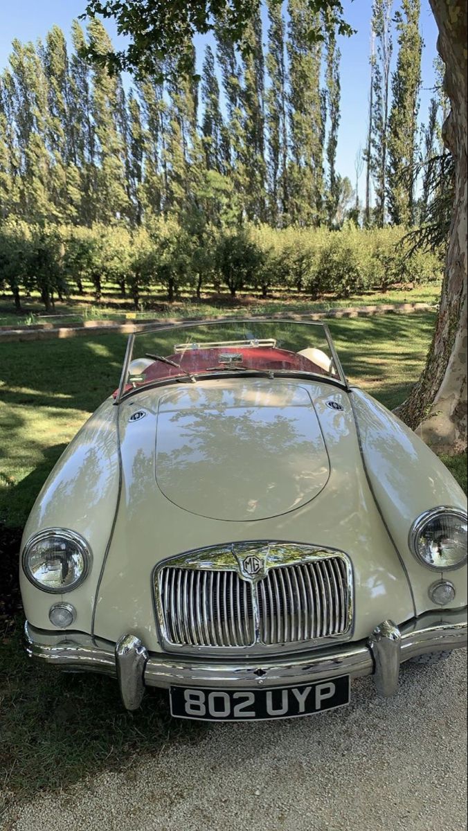 an old car is parked under a tree