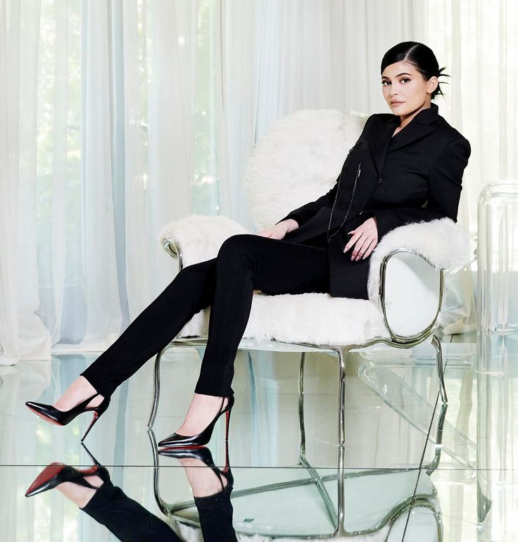 a woman sitting in a chair with her legs crossed and wearing high heeled shoes